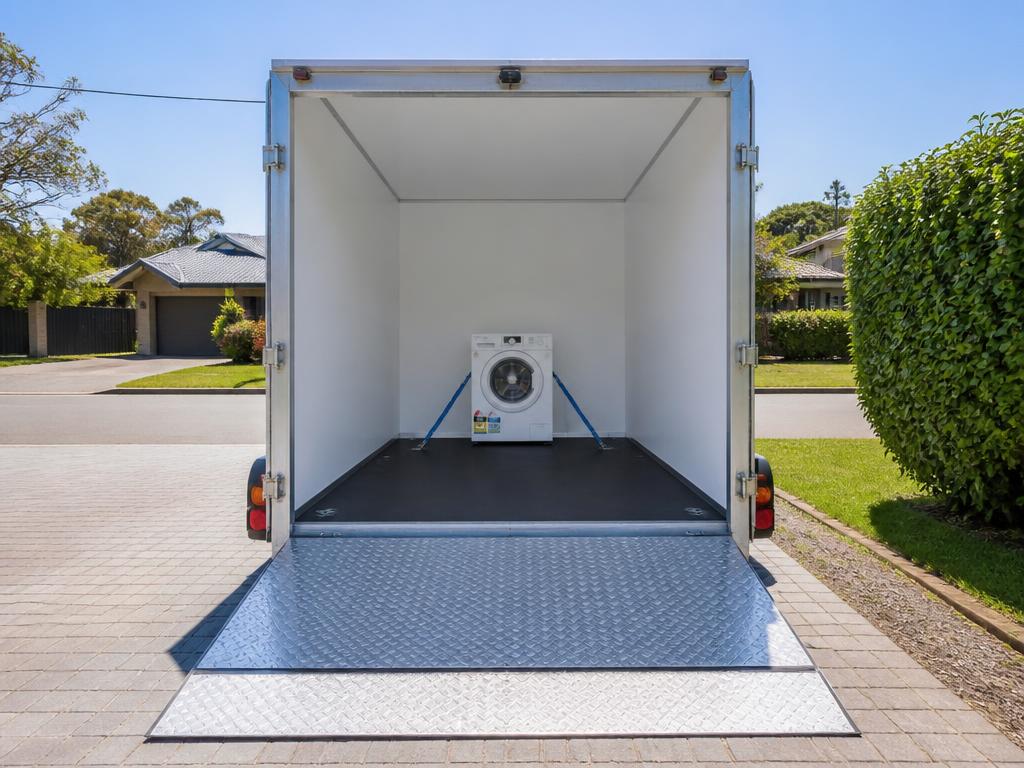Washing machine secured upright inside an enclosed trailer
